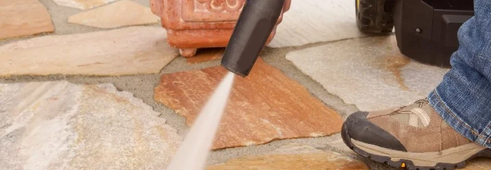 Person reinigt Terrasse mit Hochdruckreiniger